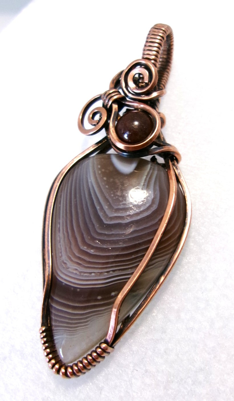 Botswana Agate gemstone copper wire wrapped crystal pendant with garnet accent bead and 2 spirals