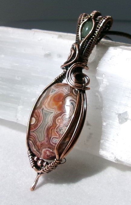 Crazy Lace Agate gemstone copper wire wrapped crystal pendant with a green aventurine gemstone set in a woven bail with copper accent beads