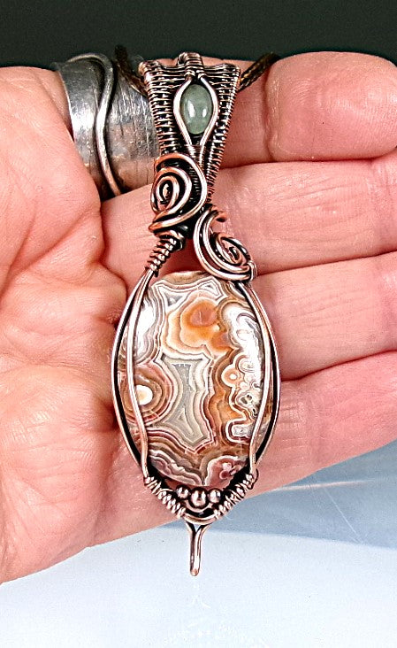 Crazy Lace Agate gemstone copper wire wrapped crystal pendant with a green aventurine gemstone set in a woven bail with copper accent beads